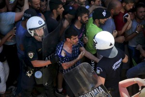 A migrant argues with a riot police officer during a registration procedure at the national stadium of the Greek island of Kos